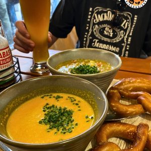 deux bols de soupe accompagnés de bretzels et d'une bière