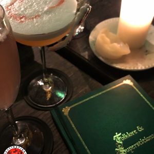 cocktails dans une ambiance feutrée avec bougie et menu 'Folklore & Superstitions'