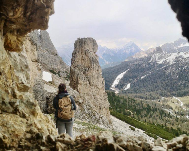 Elisa, travel planner, de dos face aux montagnes, vue depuis une cavité
