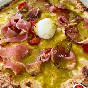 pizza typique italienne avec base crème, jambon cru, pesto pistache, tomates cerises et mozzarella