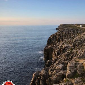 camion aménagé garé au bord d'une grande falaise plongeant dans la mer, sous la lumière du soir