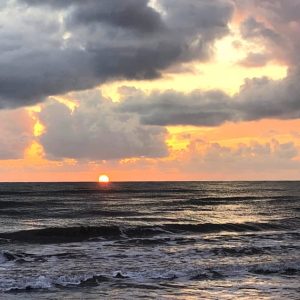 coucher de soleil sur une mer sombre avec un ciel chargé de nuages menaçants