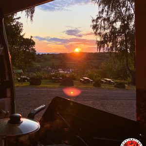 vue depuis une porte latérale de camion aménagée sur des casseroles de cuisine et un coucher de soleil en arrière-plan