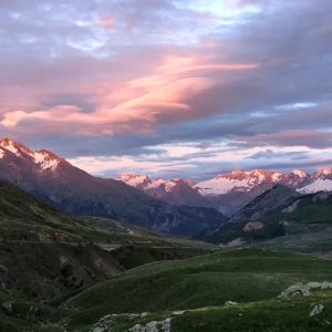 derniers rayons de soleil rosés sur une chaine de montagnes légèrement enneigée
