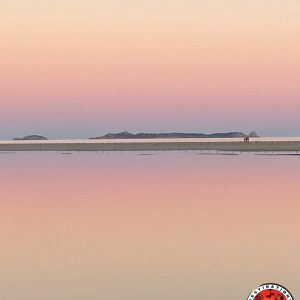 reflet symétrique du ciel dans l’eau en dégradé du rose au blanc, souvenir d'un coucher de soleil spectaculaire