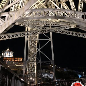 Structure métallique illuminée du pont Dom Luís Ier à Porto de nuit, vue depuis le tablier inférieur