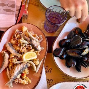 Une assiette de friture de poissons et un plat de moules servis sur la table d'un restaurant à Chioggia en Italie