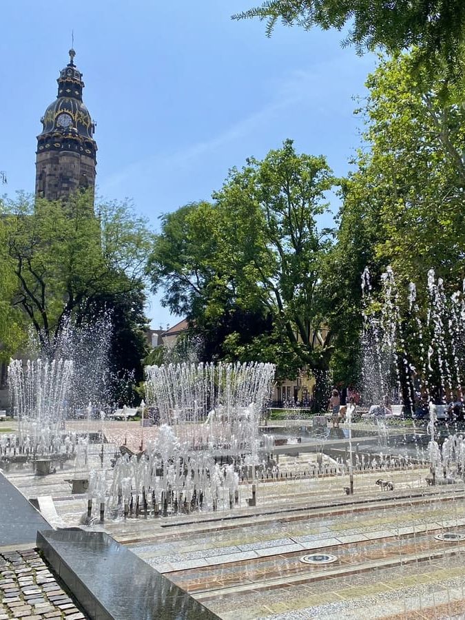 La fontaine chantante de Košice entourée d'arbres avec la tour de la cathédrale Sainte-Élisabeth en arrière-plan.
