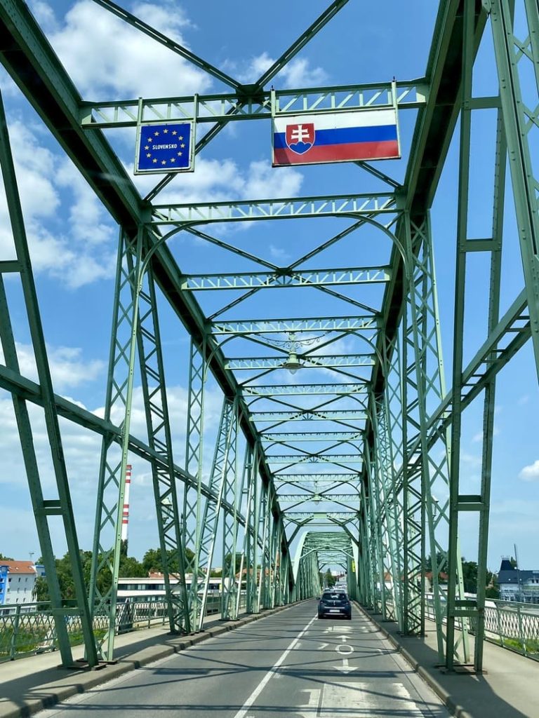 Entrée en Slovaquie par un pont métallique vert arborant le drapeau slovaque et le symbole de l'Union Européenne.